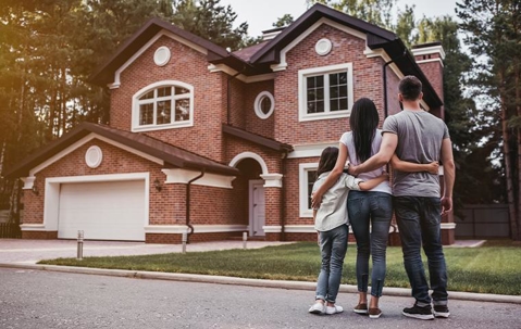 A family looking at the facade of their home